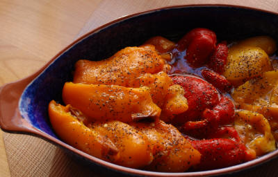 Tricolor roated peppers in blue dish with olive oil