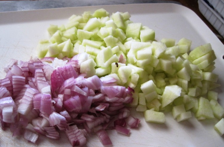 chopped apple and onion for herring salad on white cutting board